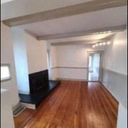 an empty living room with a wood floor and a tv