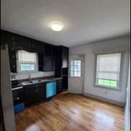 a kitchen with black cabinets and a wooden floor