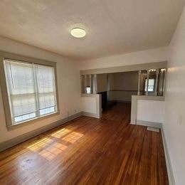 an empty living room with a wood floor and a window