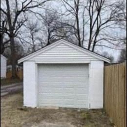 a small garage in front of some trees