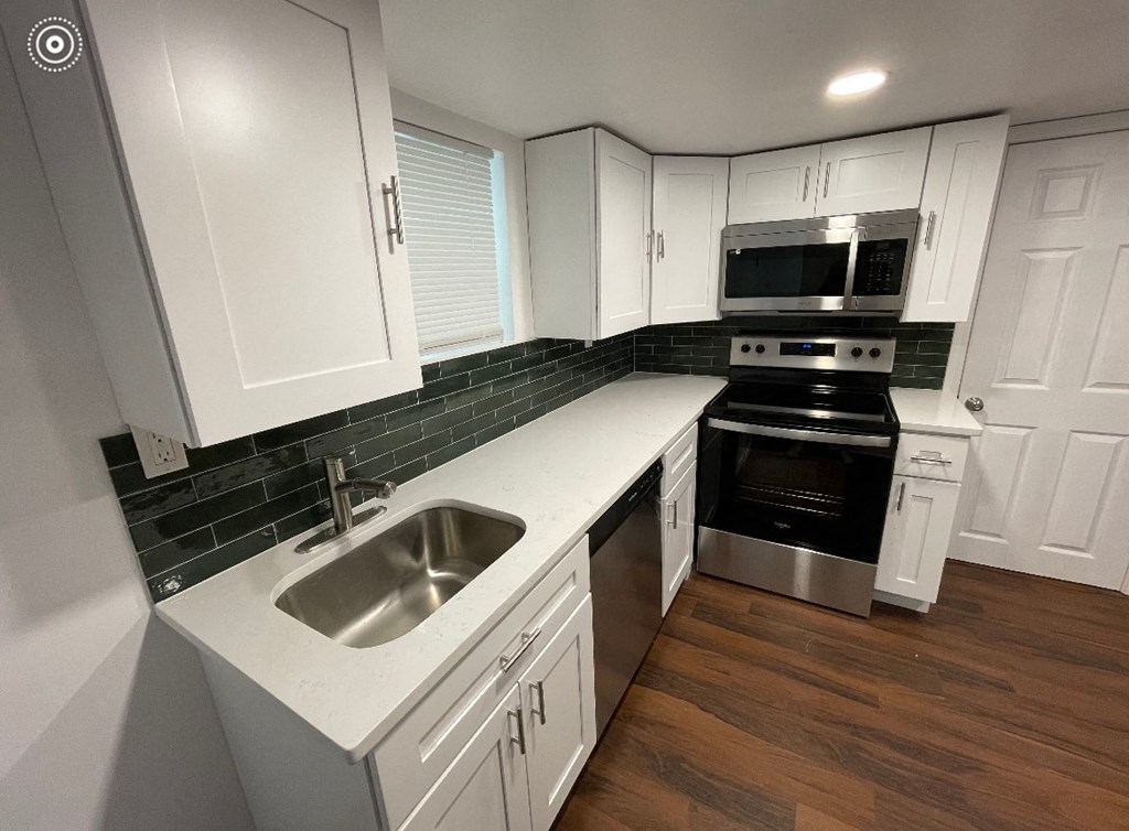 a kitchen with white cabinets and a sink and a stove