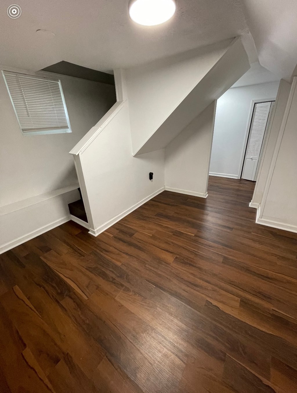an empty living room with hardwood floors and white walls