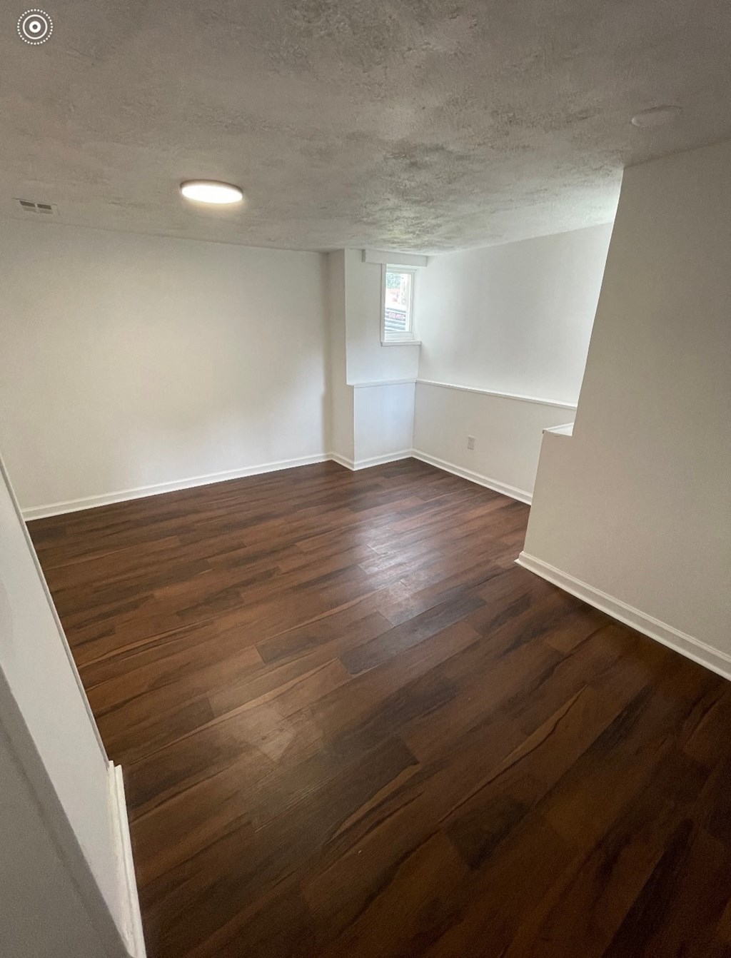 an empty living room with wood floors and white walls