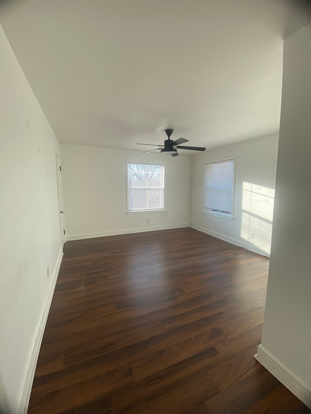 A room with a ceiling fan and wood flooring.
