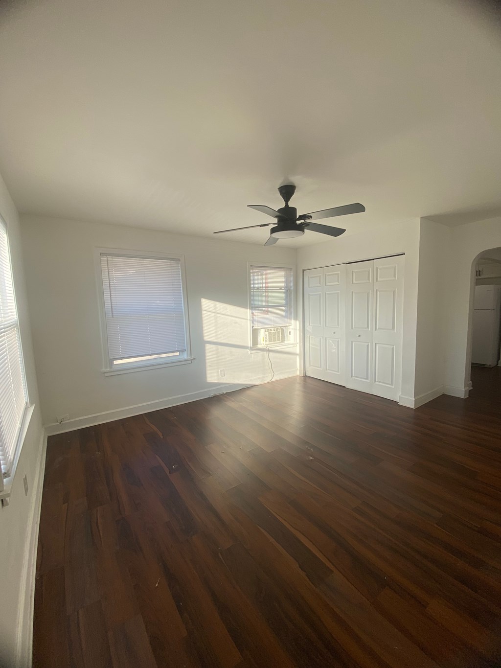 A room with a ceiling fan and wooden floors.