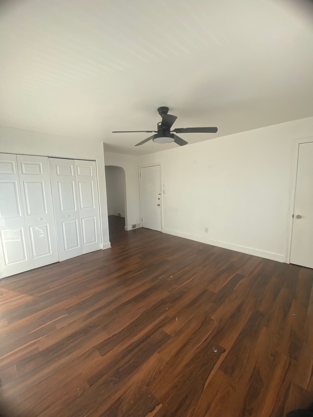 A room with a ceiling fan and wooden floors.