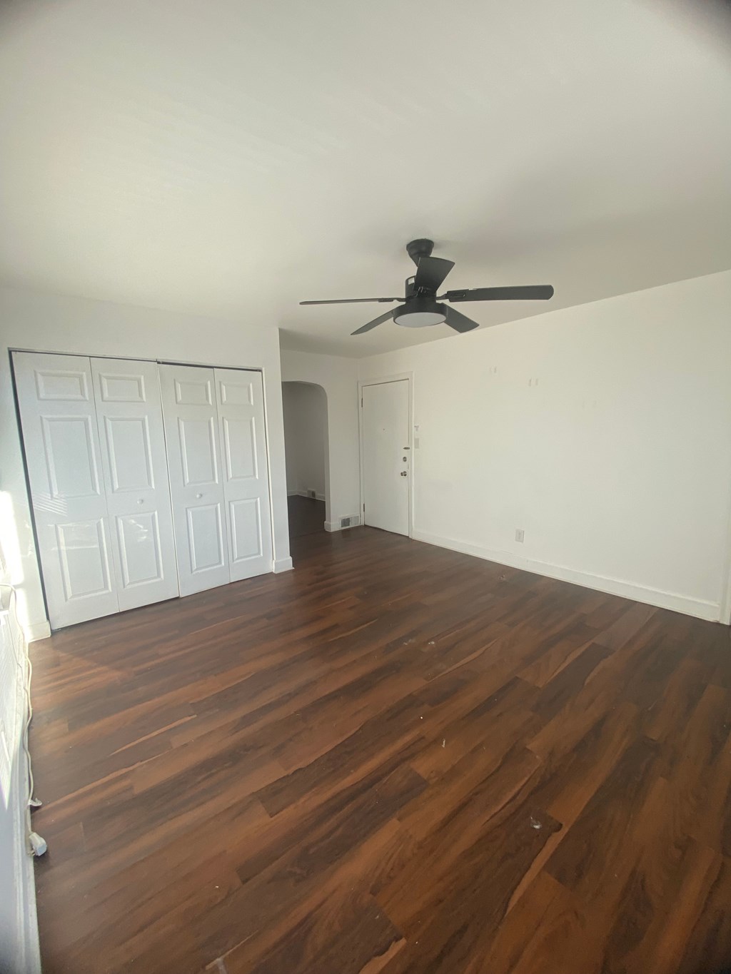 A room with a ceiling fan and wooden floors.