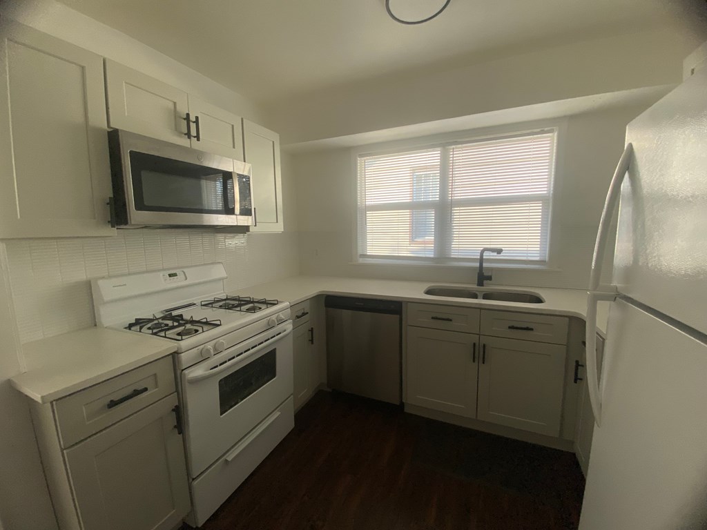 A kitchen with a stove, sink, and refrigerator.