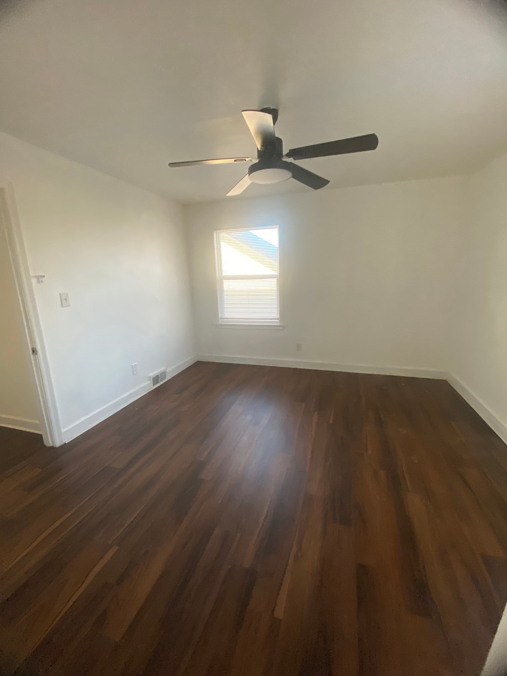 A room with a ceiling fan and wooden flooring.