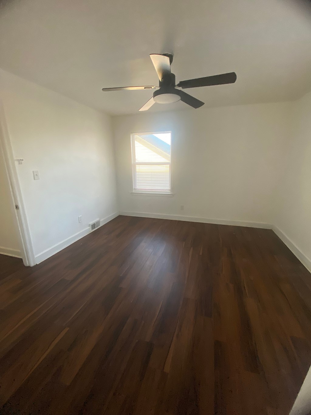 A room with a ceiling fan and wooden flooring.