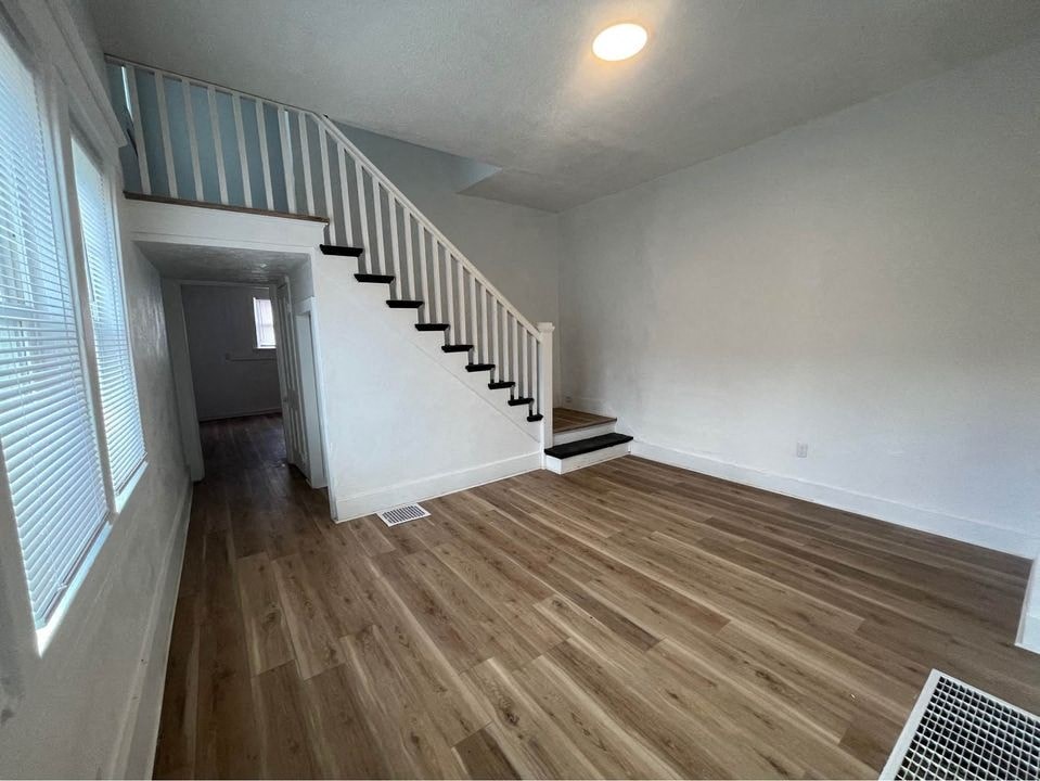 an empty living room with wood floors and a staircase