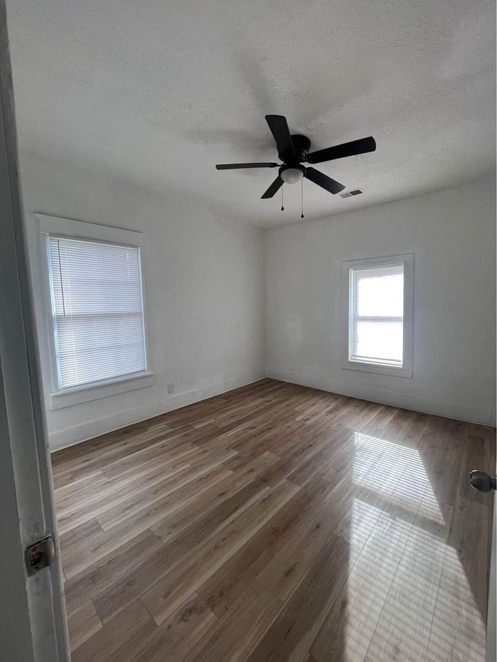 an empty living room with a ceiling fan and wood floors