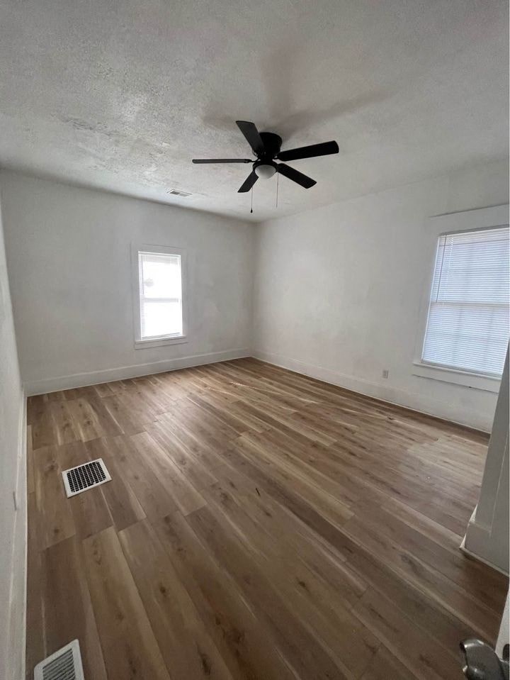 an empty room with wooden floors and a ceiling fan