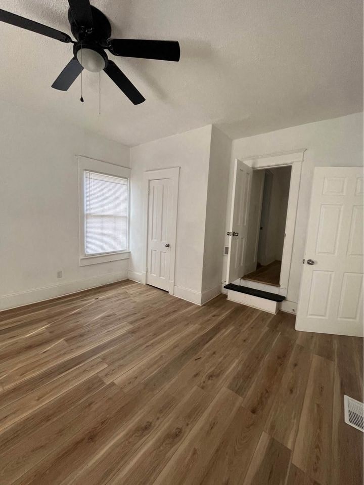 an empty living room with hardwood floors and a ceiling fan