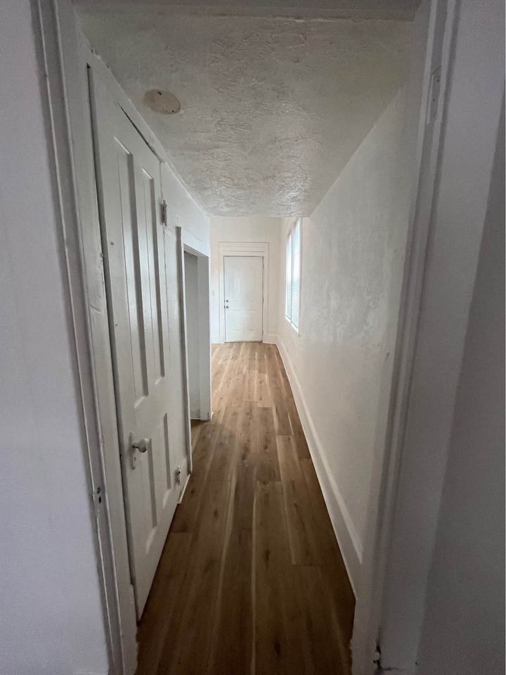 a hallway with white walls and wooden floors