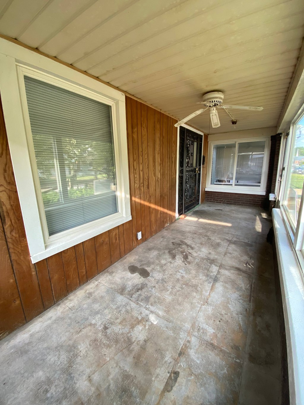 A room with a ceiling fan and two windows.