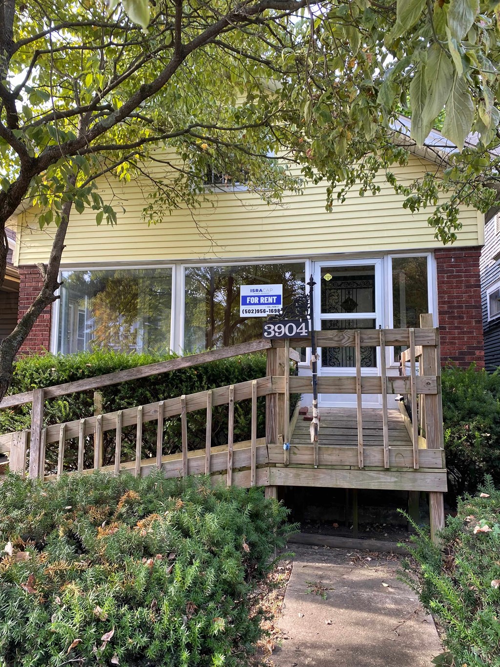 A house with a yellow siding and a sign that says "3904".