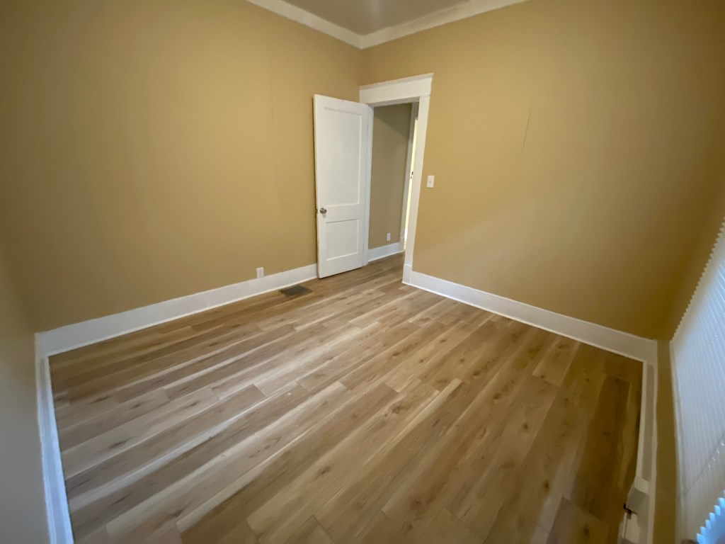 A room with wooden flooring and a white door.