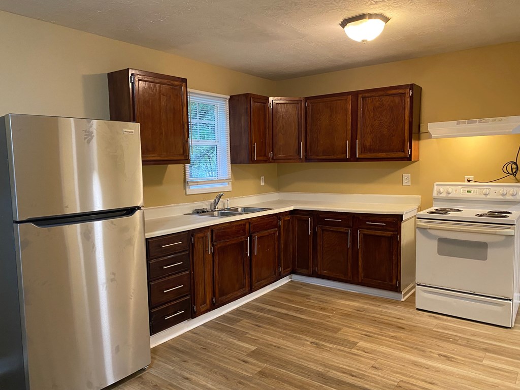 A kitchen with wooden cabinets and a stainless steel refrigerator.