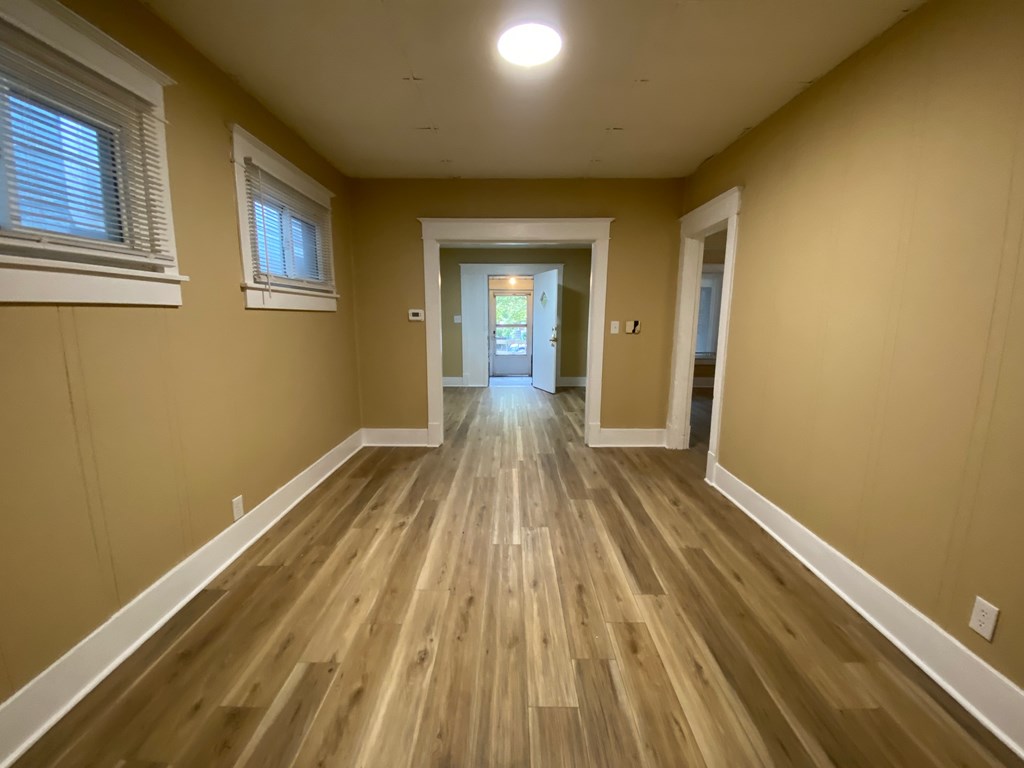 A long, narrow hallway with wooden floors and white trim.