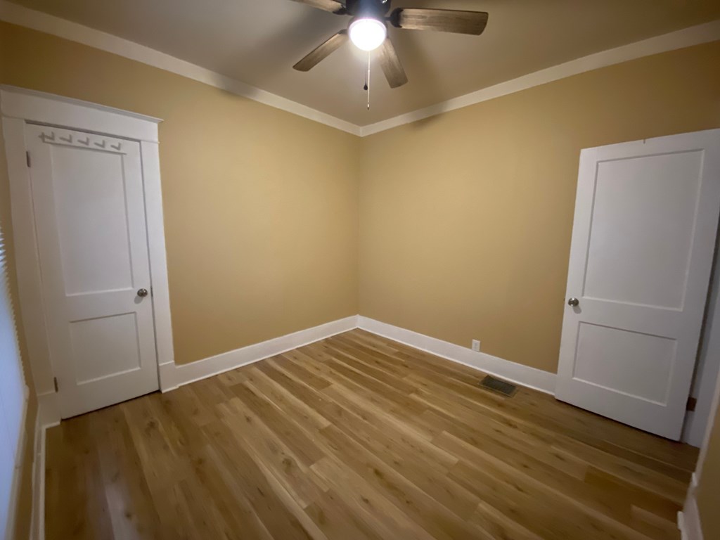 A room with a ceiling fan and wooden flooring.