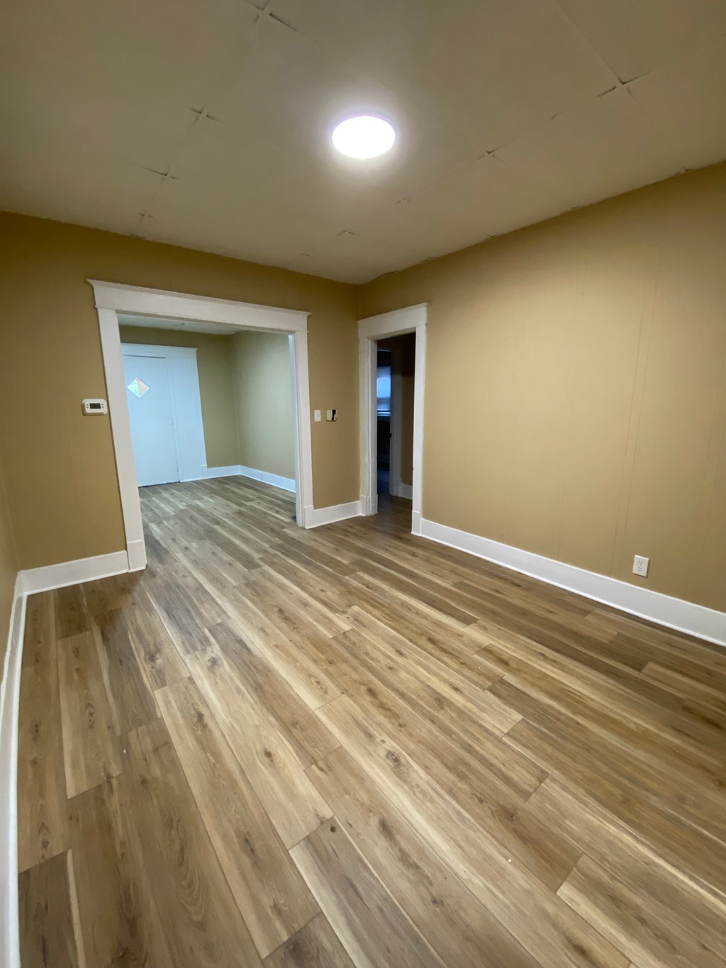A room with wooden flooring and a white ceiling light.