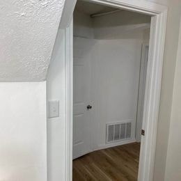 A white door is open to a room with a white wall and a white door.