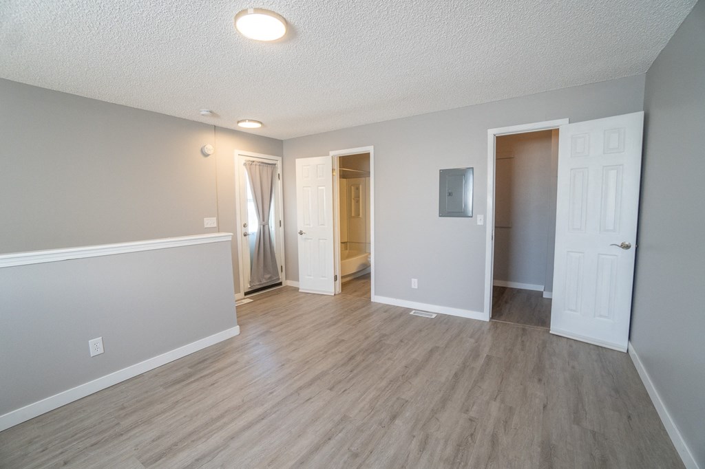 an empty living room with wood flooring and white walls