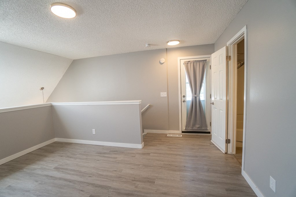 an empty room with a hallway and a door to a closet