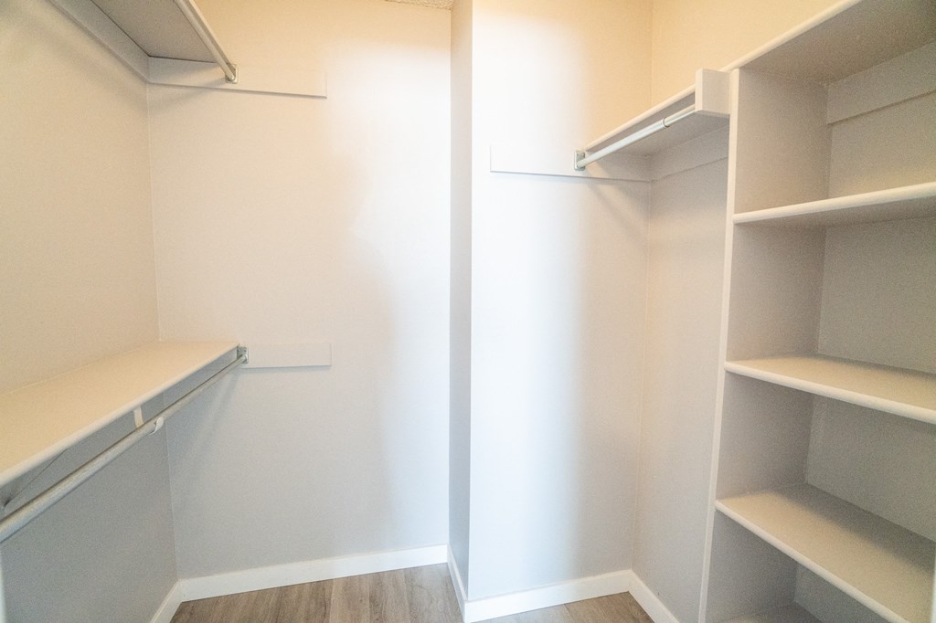a walk in closet with empty shelves and a white wall