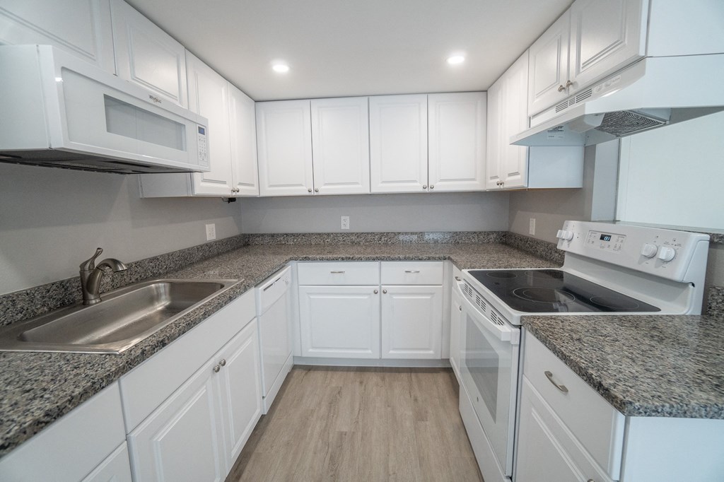 an empty kitchen with white cabinets and granite counter tops