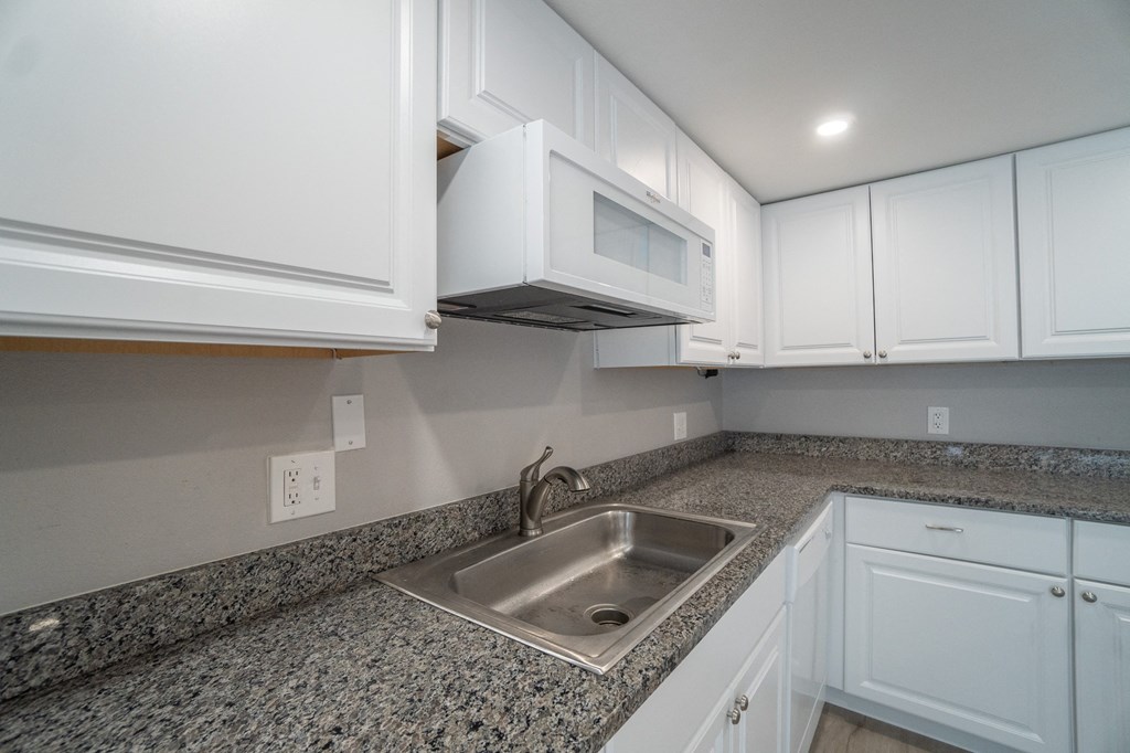 a kitchen with white cabinets and granite counter tops and a sink