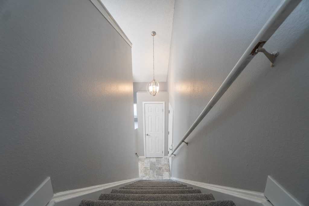 a landing with stairs and a white door and a chandelier