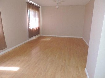 an empty living room with wooden floors and a window