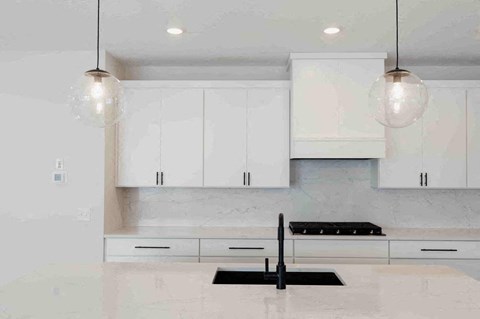 an all white kitchen with white cabinets and a black sink