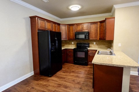 A kitchen with wooden cabinets and black appliances.