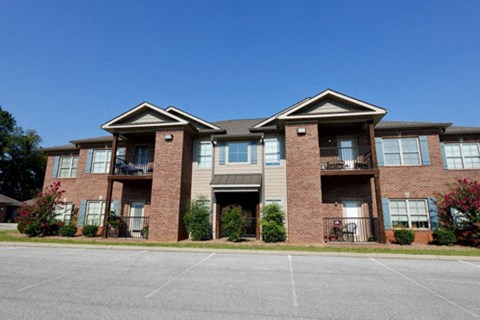 A large brick apartment building with a parking lot in front.