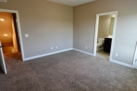 A room with carpeted floor and two doors.