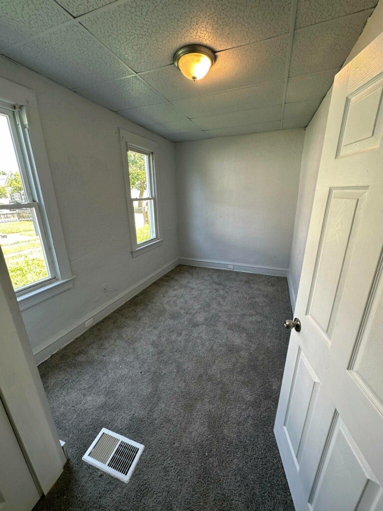 a small room with a carpeted floor and two windows