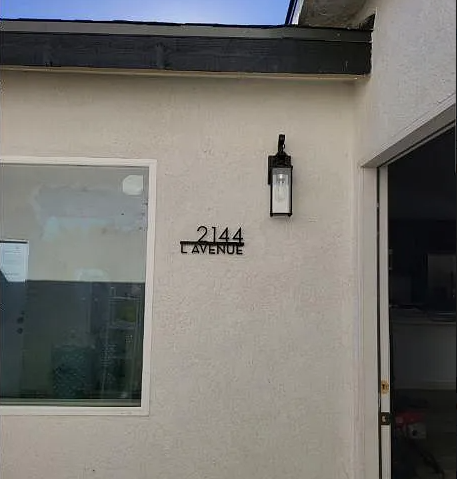 A white house with a black lantern on the wall and a window.