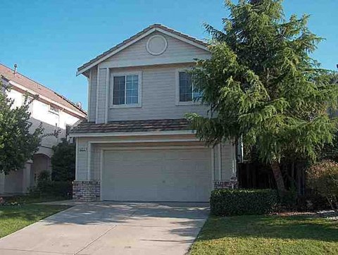 a white house with a garage door and a tree