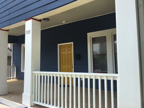 the front porch of a blue house with a yellow door