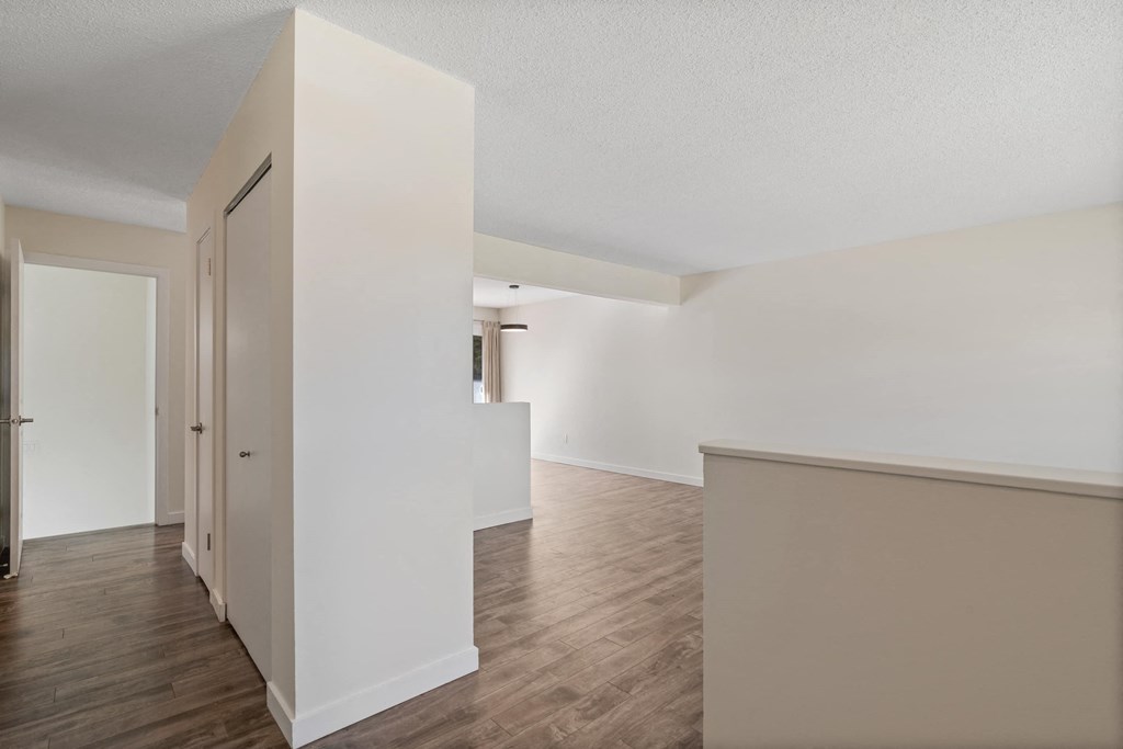 a living room and dining room with white walls and wood floors