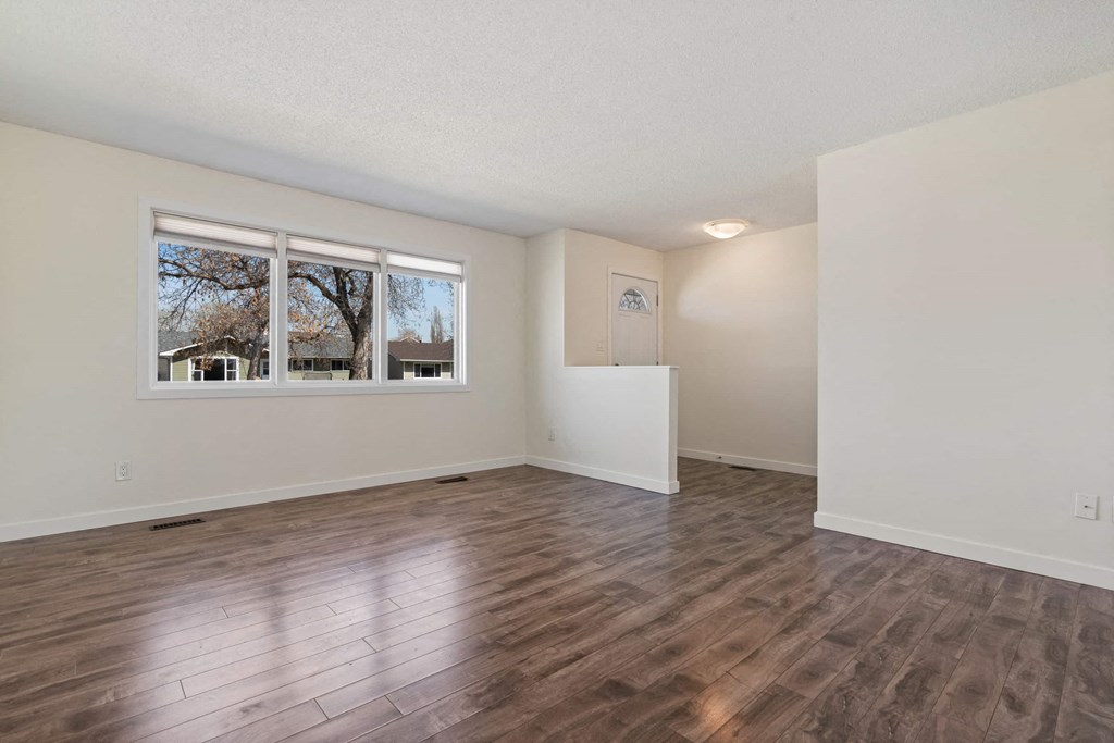 an empty living room with a window and wood floors