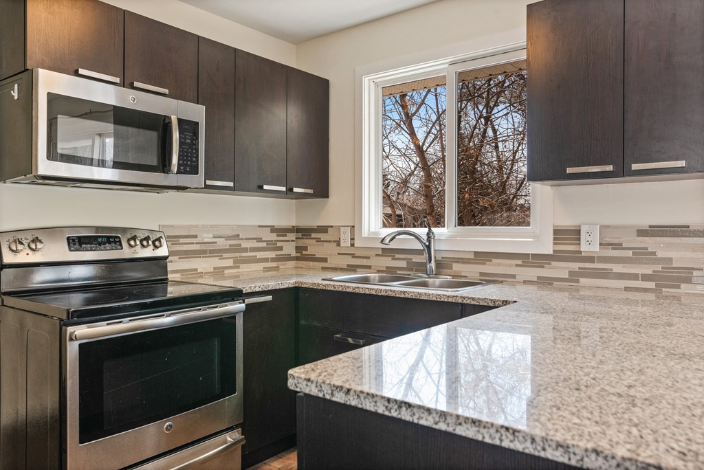 an updated kitchen with granite counter tops and black appliances