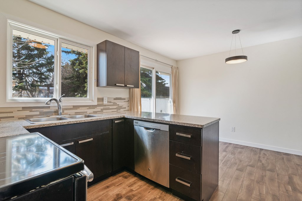 an empty kitchen with black cabinets and a window