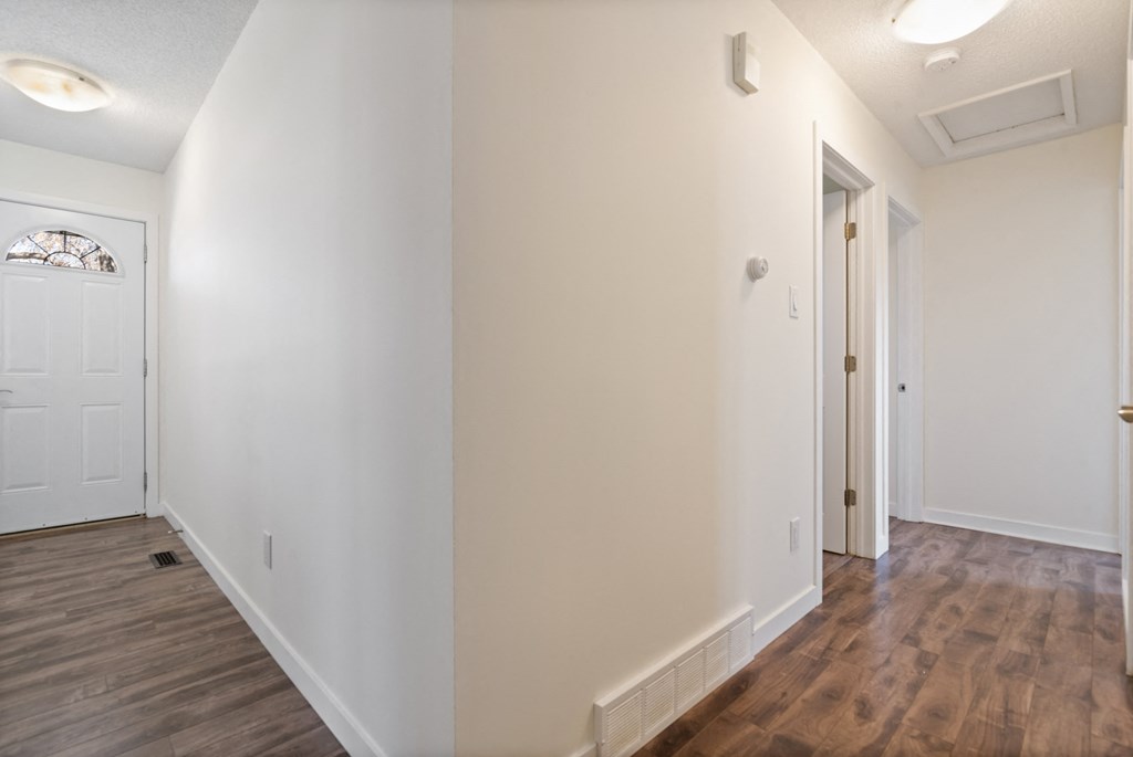 a living room with white walls and wood flooring and a white door