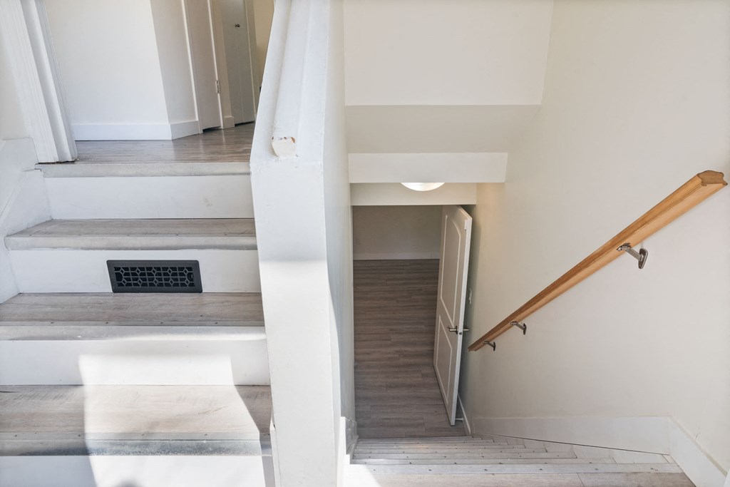 a staircase in a home with white walls and wood floors