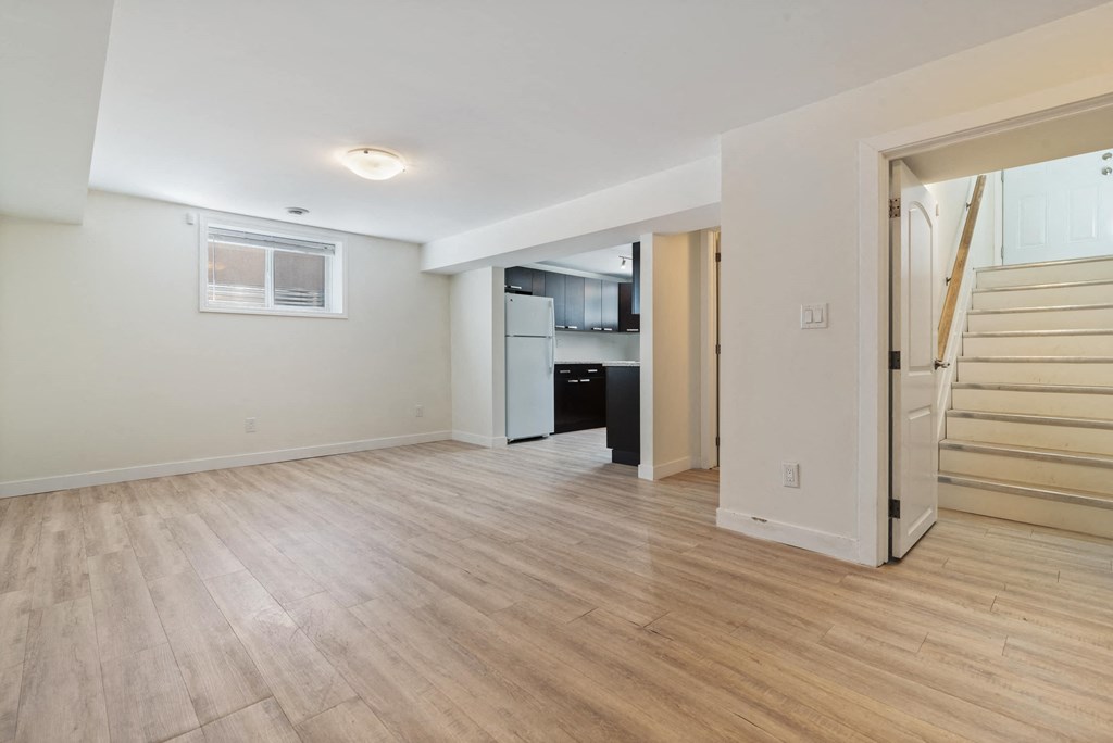a renovated living room with a staircase and a kitchen in a home