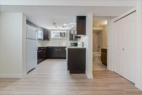 a renovated kitchen with black cabinets and white walls and wood floors